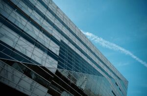 A striking low angle view of a modern glass building against a clear blue sky, emphasizing urban architecture.