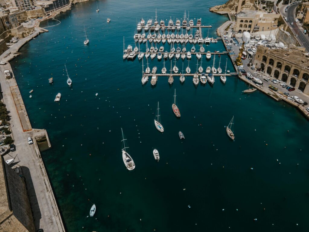 Stunning aerial shot of Birgu Marina with yachts and boats docked in vibrant blue waters.